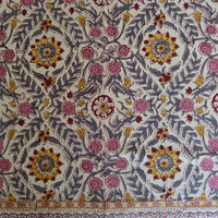 Détail du blockprint de la nappe Suman : rosaces safran à cœur rouge, fleurettes roses et feuilles ardoise